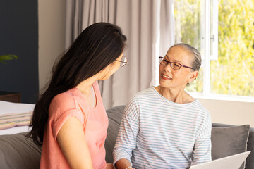 Smiling asian grandmother and granddaughter talking indoors