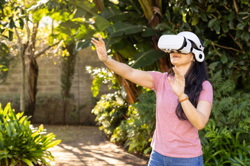 Using VR headset, Asian woman interacting with virtual environment outside