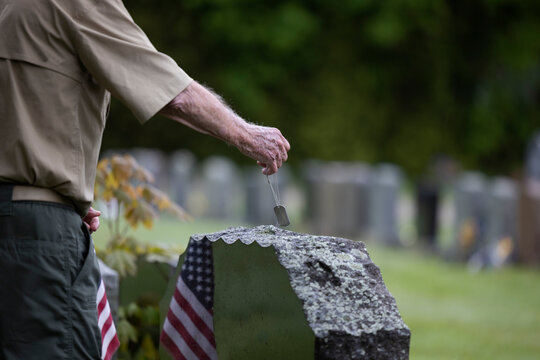 Senior Citizen military man alone at cemetary with dog tag 