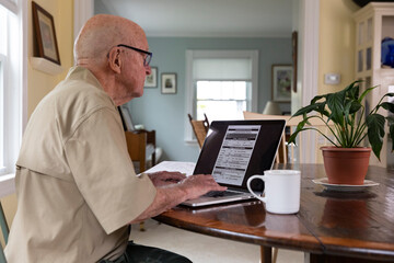 Senior on computer apply Veteran Medical benefits kitchen table