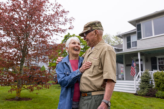 Happy Senior Citizen Veteran Portrait front of home  hug wife 