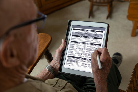 Senior on tablet computer apply Veteran Medical benefits form