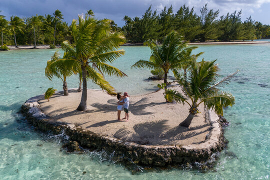 A man and woman alone together on a tiny tropical island in the shape of a heart. The romantic getaway is a private vacation for the married couple in paradise. 