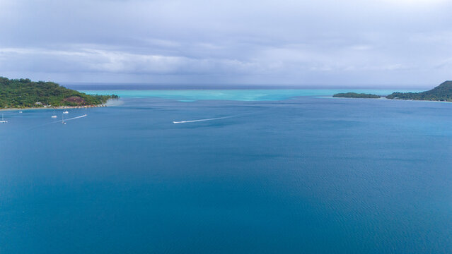 Aerial view captured by drone of the beautiful blue and azure colored ocean sea water surrounding the tropical island of Bora Bora in French Polynesia. 