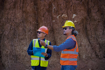 Two young male construction workers are surveying using blueprints in the field