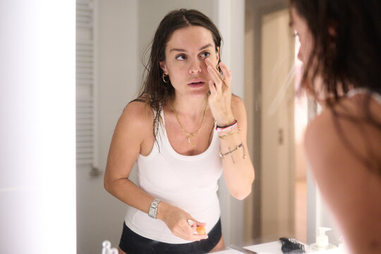 Woman Applying Eye Cream in Bathroom