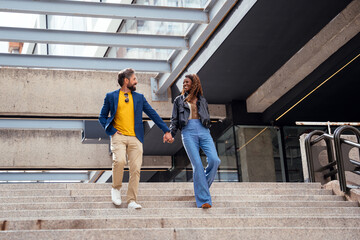 Stylish couple walking hand in hand down city stairs