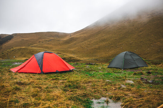 Green and red  outdoor tents in foggy morning near lake.