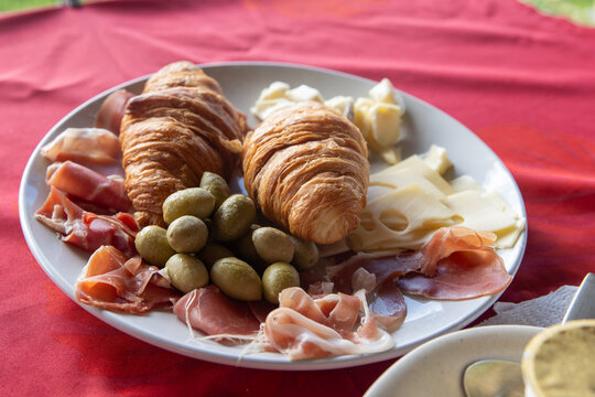 Breakfast plate in French Polynesia with cheese, fresh baked croissant, meat, olives, poisson cru and more food. 