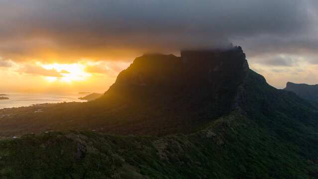 Sunset over Mount Otemanu on tropical island Bora Bora in French Polynesia. Low clouds float above the extinct volcano on the popular tourist destination in the south pacific sea. 