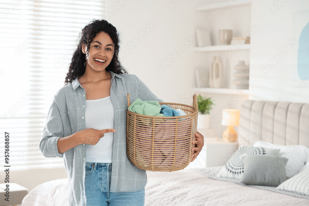 Poster Happy woman with basket full of laundry in bedroom