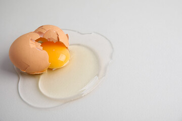 Broken raw egg with shell on light grey background, closeup. Space for text