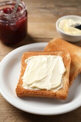 Delicious toasted bread slices with butter served on wooden table, closeup