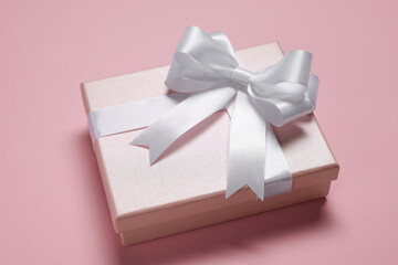 Gift box with bow on dusty pink background