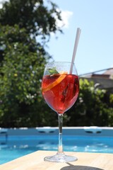 Tasty cocktail in glass near swimming pool outdoors