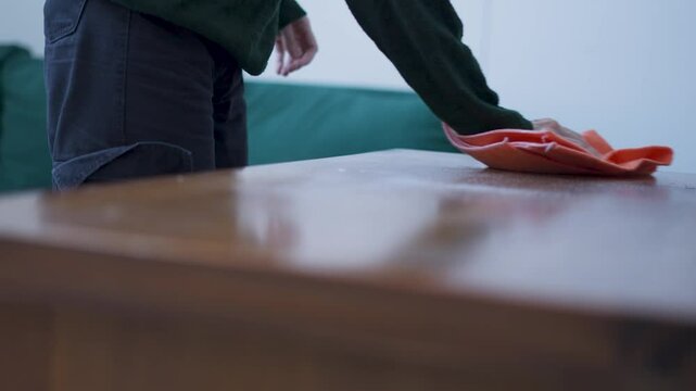 Mujer pasando un trapo naranja sobre un mueble de madera. Limpiar, limpieza. Trapo. Hogar. Servicio de limpieza. Footage de limpieza. 