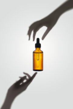 Pipette bottle with cosmetic oil in female hand on a light background
