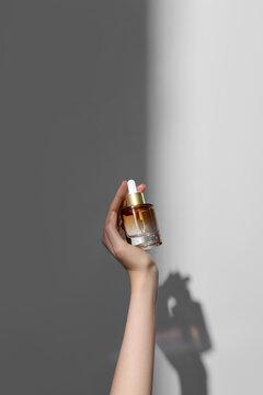 Hand holding Natural Serum Oil bottle on white background