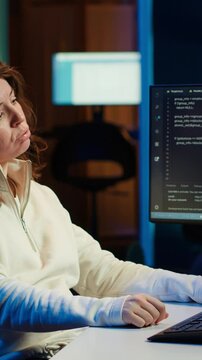 Vertical video Tired woman hurting from too much stress accumulated while doing software quality assurance on computer. Developer suffers from headache after inspecting coding on PC for too long