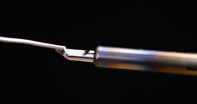 hot soldering iron and solder on a black background, melting solder on a red-hot soldering iron