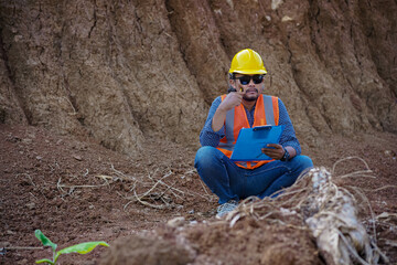 A male construction worker is inspecting and recording data in the field