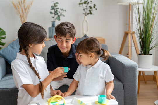 Three young children playing tea party