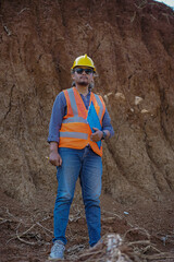 A male construction worker is inspecting and recording data in the field