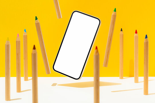 White screen telephone mockup and coloring pencils, hovering on yellow