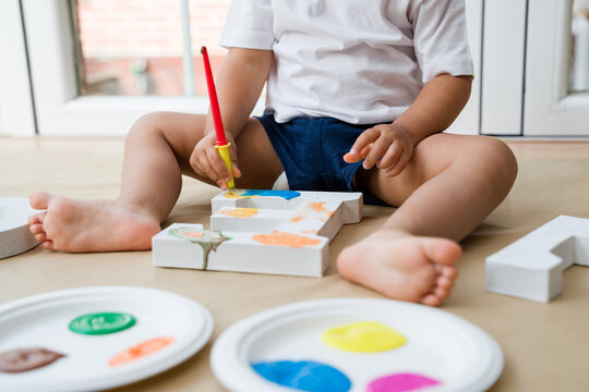 Toddler painting wooden letter e at home