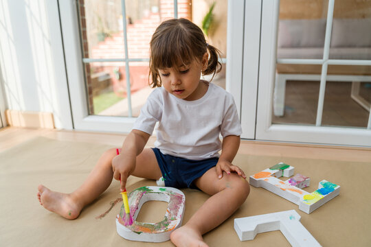girl painting wooden letters at home