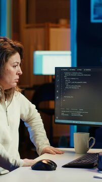 Vertical video Programmer doing software quality assurance, stretching arms behind back after reading source code, feeling fatigued. IT expert takes break from work to relax muscles after inspecting