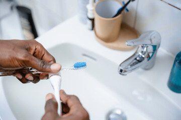 The man squeezes the paste onto the brush