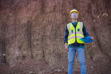 A male construction worker is inspecting and recording data in the field