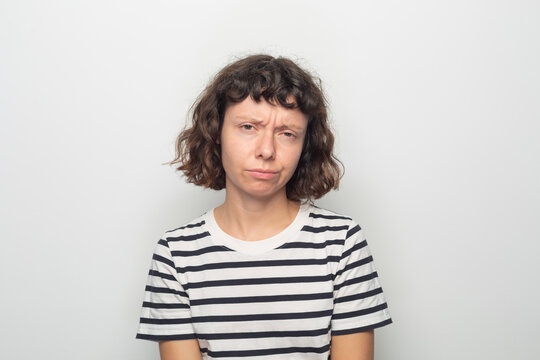 Curly-haired woman with striped shirt and slight frown.