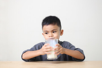 Asian child drinking milk on white background. Smiling of Asian boy with a glass of milk.