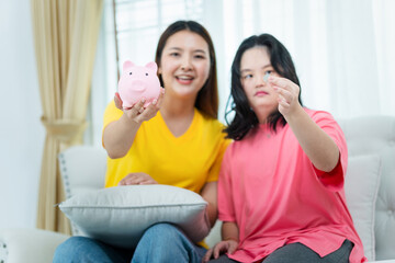 Young woman and friend holding piggy bank and coin showing for saving money in living room