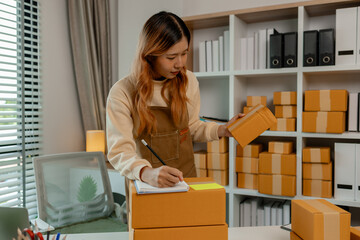 a beautiful female employee is packing clothing items into parcel box with great preparation...