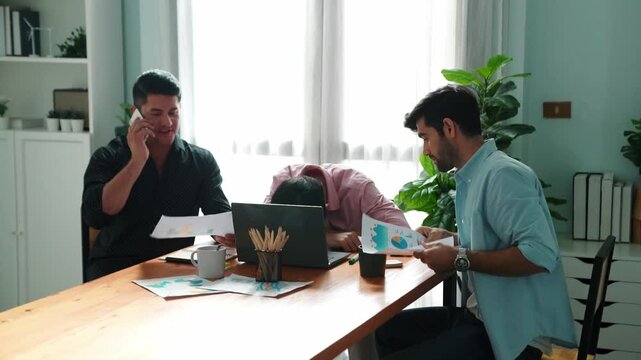 Professional businessman waking tired partner fall asleep or taking a nap while project manager calling phone and talking about marketing campaign. worker using phone to talk to investor. Convocation.