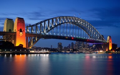 Fototapeta premium Harbour Bridge at Night: Illuminated Sydney Skyline with Reflections Background