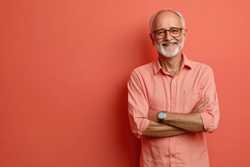 Fototapeta premium Senior male presenter, smiling confidently, in front of a solid light coral background with ample space for copy