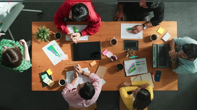 Top view of businesswoman sharing idea while stand at white board while manager asking question at table with tablet display financial graph. Attractive female leader pointing at board. Convocation.