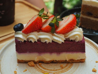 cheesecake with strawberries. Blueberry cheesecake topping with fresh sliced strawberry serving on the plate. Famous sweet dessert menu in coffee shop. 