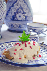 Authentic mexican Chiles en Nogada, roasted and stuffed poblano pepper with walnut white sauce and fresh pomegranate, served over talavera plate at Puebla city, Mexico.