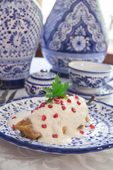 Chiles en Nogada, roasted and stuffed poblano pepper with walnut white sauce and fresh pomegranate, served over talavera a plate.