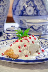 Chile en Nogada with walnut sauce served over talavera plate, vertical close-up.