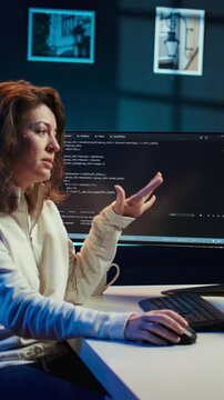 Vertical video Woman doing software debugging helped by coworker in videocall, checking errors in lines of code. Programmer working from home fixing coding mistakes, assisted by colleague in