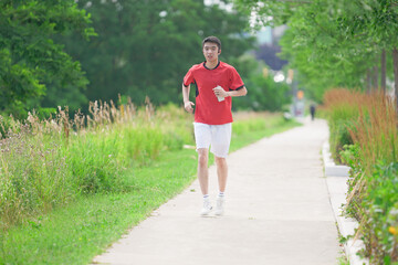 A young man is jogging with music in the city.