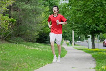 A young man is jogging with music in the city.