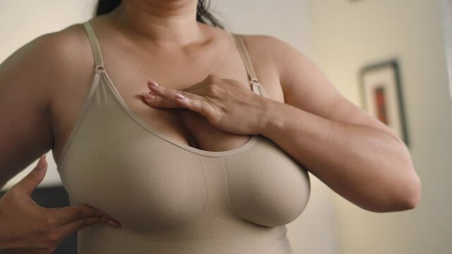 Close-up of adult Hispanic woman examining her body at home for brechest ast cancer.