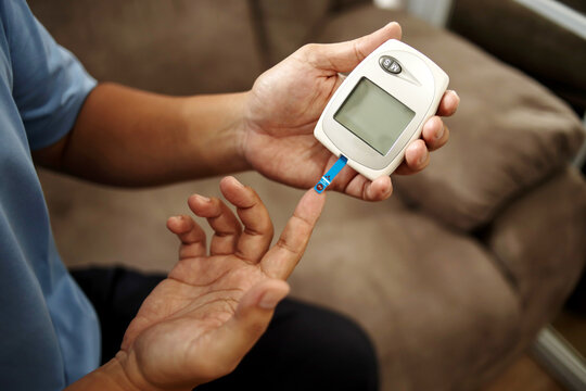 Diabetes checking blood sugar level. Man using lancelet and glucometer at home.